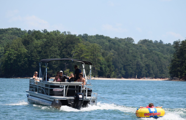 A rental deck boat pulling a tube across Lake Lanier
